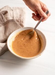 Mixing a creamy sauce in a small bowl with a spoon.