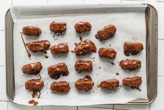 18 small homemade chocolate coated candy bars on a baking sheet lined with parchment paper.