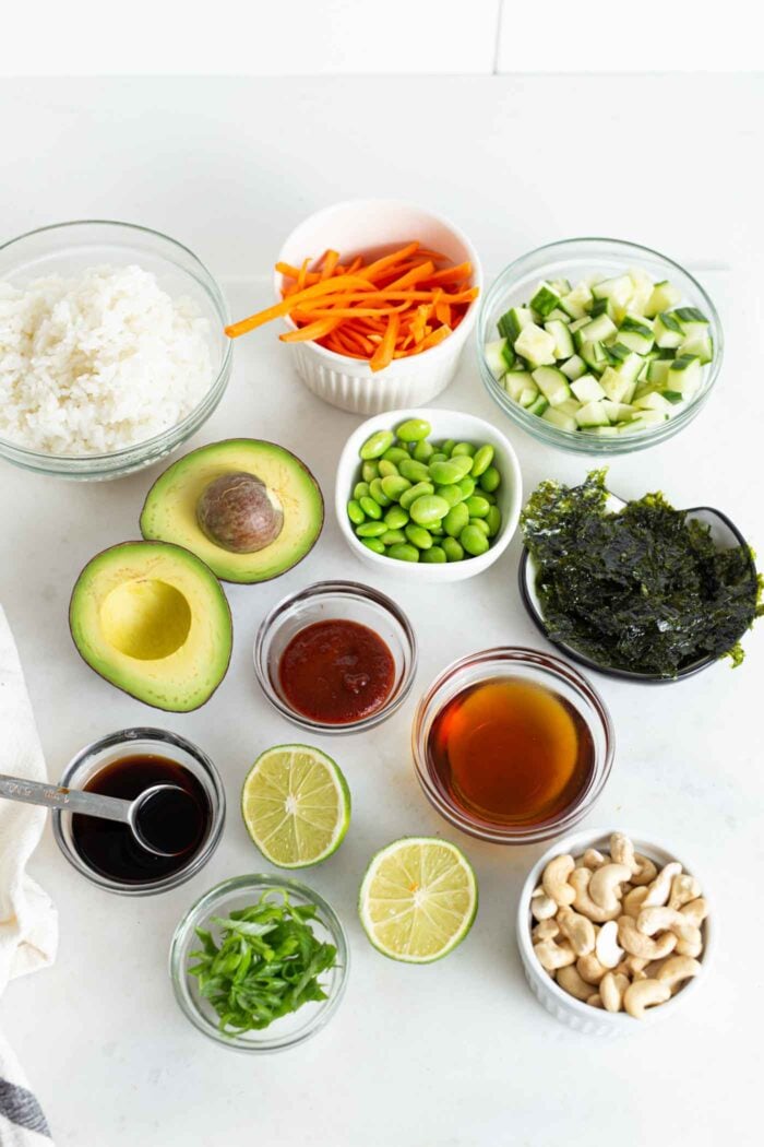 Various ingredients for making sushi in small dishes on a kitchen counter.
