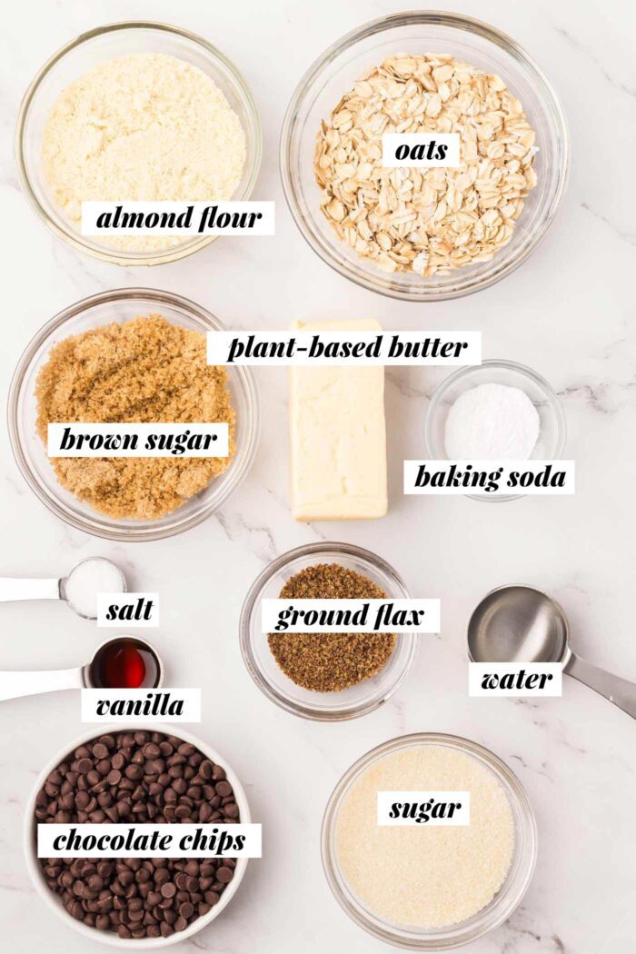 All of the ingredients needed for making an almond flour oatmeal chocolate chip cookie recipe. Each ingredient is labelled with text.