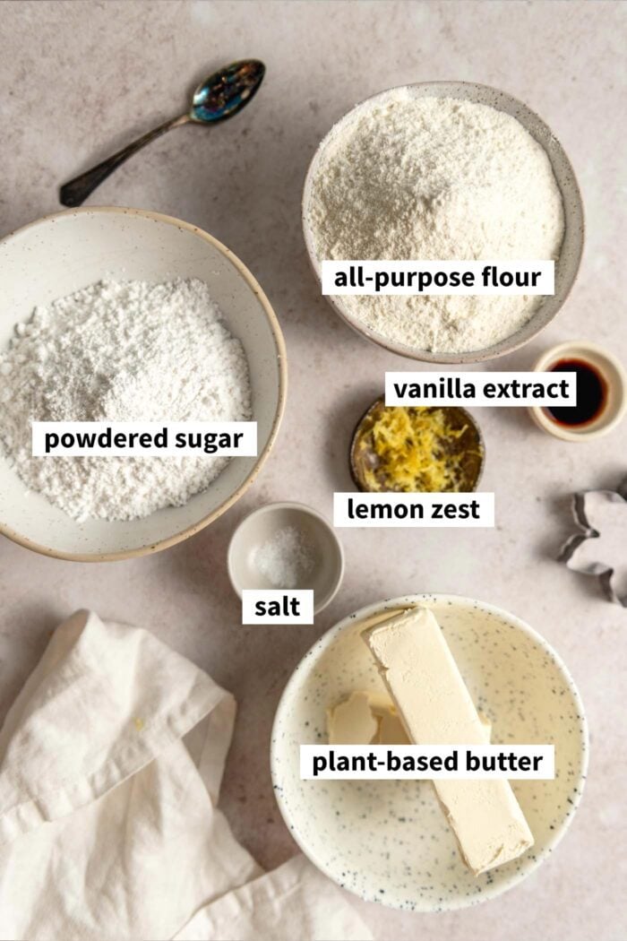 The ingredients needed for making a lemon shortbread cookie recipe. Each ingredient is labelled with text overlay.