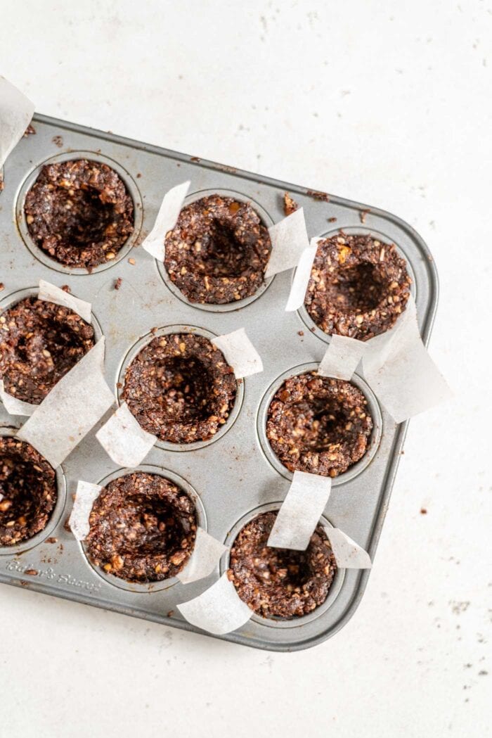 Unfilled chocolate tarts in a mini muffin tin.
