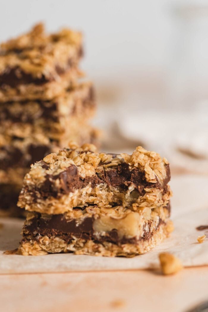 Close up of an oatmeal chocolate fudge bar with a bite taken out of it so you can see the texture inside the bar. There are more bars in the background.