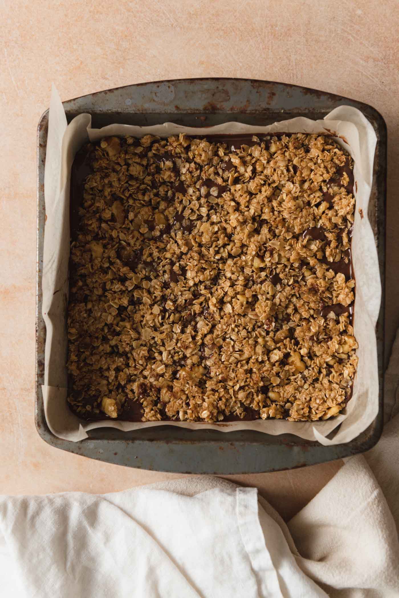 Overhead view into a pan of oat fudge bars with a crumble oatmeal layer on top.