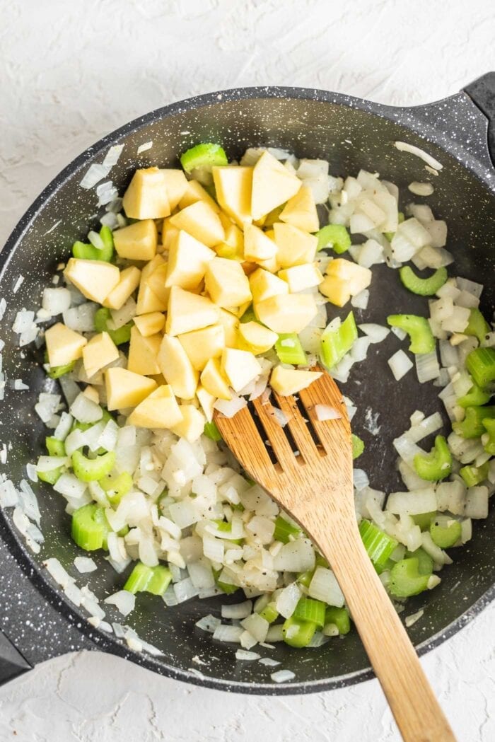 Apple, celery, onion and garlic in a skillet with herbs.
