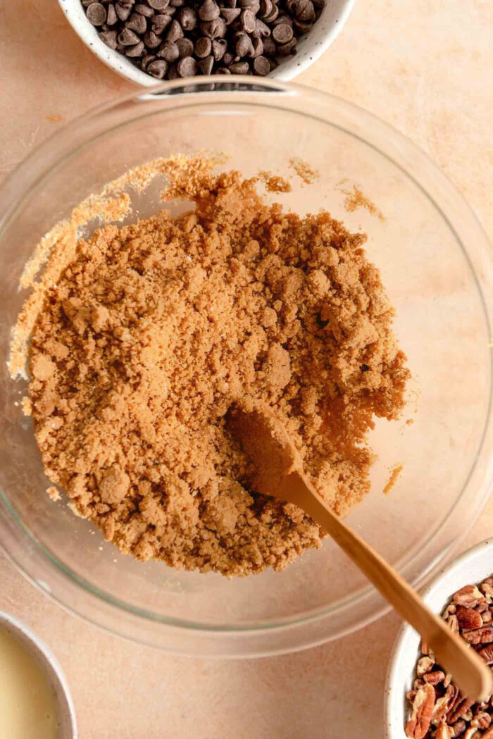 Graham cracker crumbs in a mixing bowl with a small wooden soon resting in it.