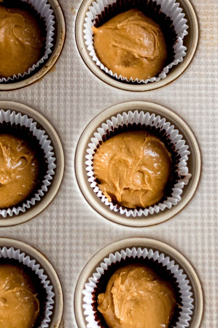 Overhead image of peanut butter spooned into a lined muffin tin.