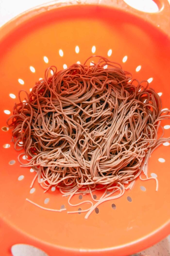 Cooked soba noodles in a large strainer.