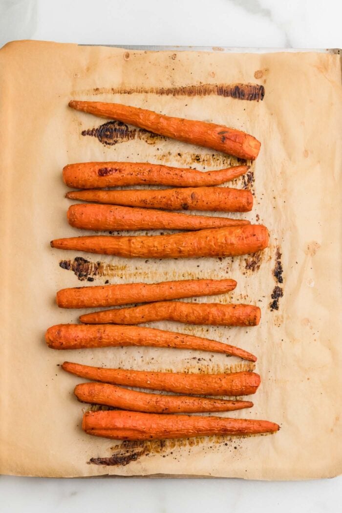 Whole roasted carrots on a baking tray.