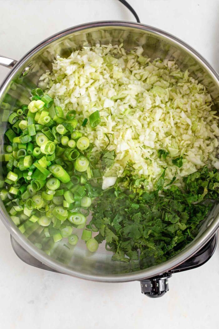 Cabbage, green onion and cilantro cooking in a skillet.