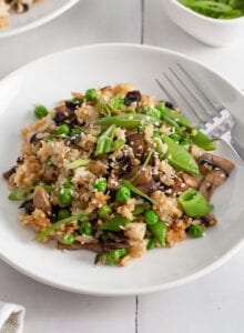 Mushroom fried rice topped with scallions and sesame seeds in a bowl.