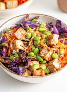 Colourful bowl of rice, tofu, edamame, cabbage and grated carrot.