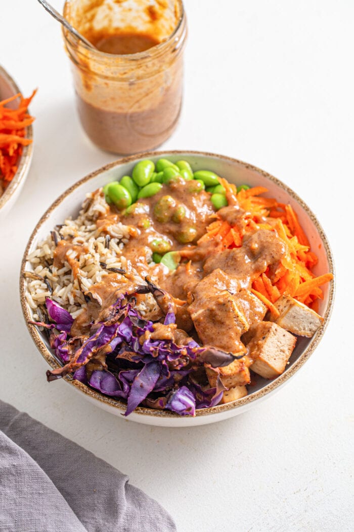 Bowl of cabbage, rice, tofu, carrot, edamame. Topped with creamy peanut sauce.