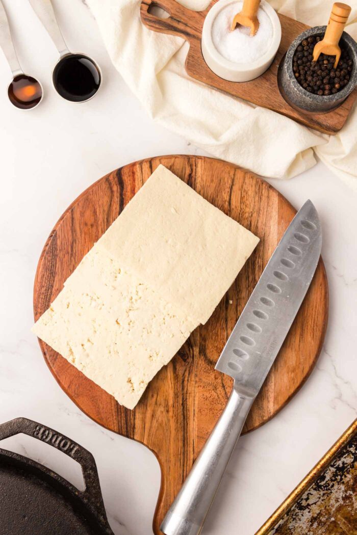 Slab of tofu cut into 3 slices on a cutting board.